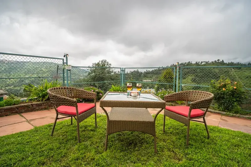 Balcony seating area with chairs facing valleys and mountains at Adrushya Estates