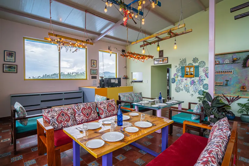 Indoor dining area with multiple tables set with plates and sofas at Adrushya Estates