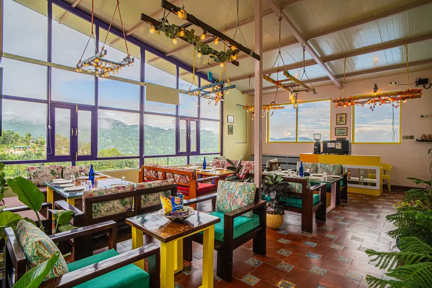 Indoor dining space with panoramic windows overlooking hills at Buransh by Adrushya