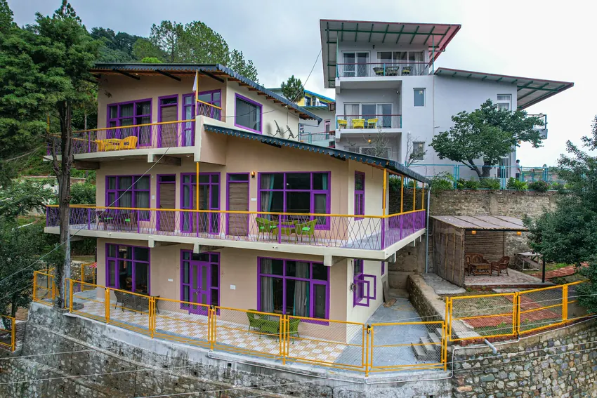 Multi-storey building with balconies, wooden railings, and greenery at Adrushya Estates