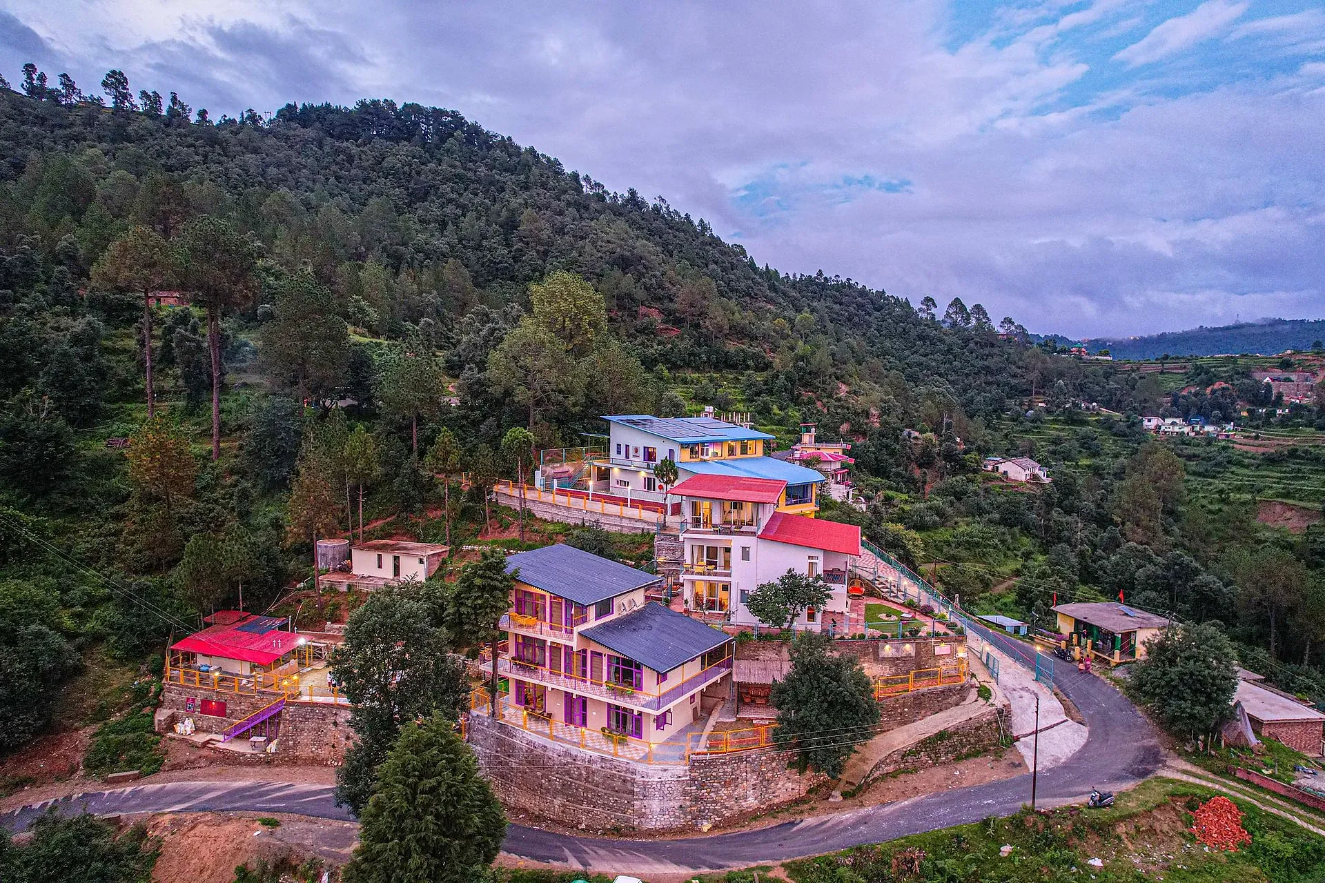 Hillside resort architecture and surrounding pine forest at Adrushya Estates