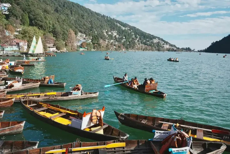 Boats floating on scenic mountain lake surrounded by forested hills